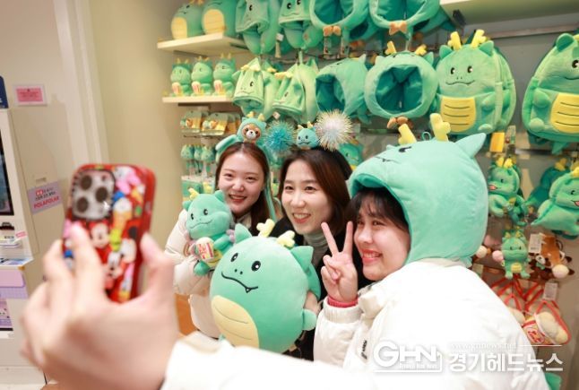 시민들이 26일 에버랜드 기프트 샵에 진열된 용인특례시 공식 캐릭터 조아용과 에버랜드 인기 캐릭터 레시의 캐릭터 협력 상품을 착용하고 사진을 찍고 있는 모습.